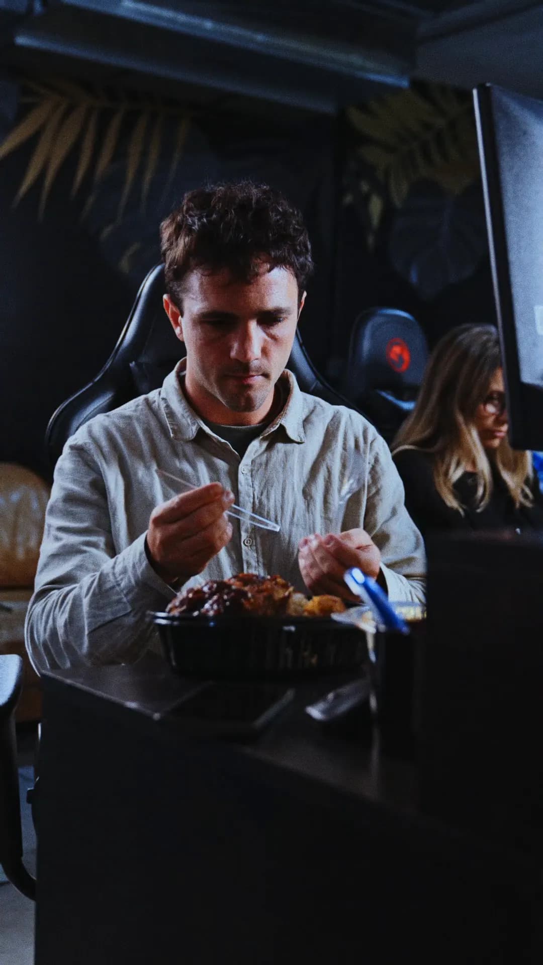 En la oficina, un chico intenta comer pollo con un tenedor descartable que no aguanta, hasta que le alcanzan una ProteAr.